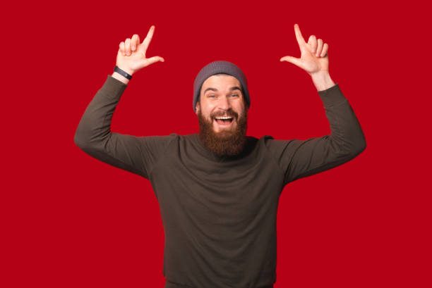 istock Cheerful amazed bearded man is pointing up, above his head. 1346167910