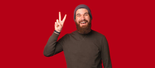 istock Wide smiling bearded man is making peace or victory gesture at the camera. 1346167928