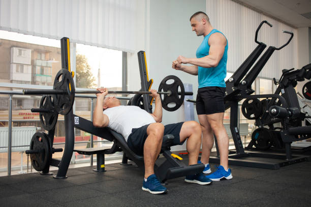 istock coach teaches the man the correct technique of performing the exercise on the simulator in the gym. Weight loss, muscle building, healthy lifestyle, active, indoor. 1346169582