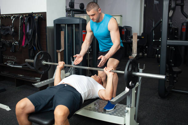 istock coach teaches the man the correct technique of performing exercise on the simulator in the gym. Weight loss, muscle building, healthy lifestyle, active, indoor. 1346170199