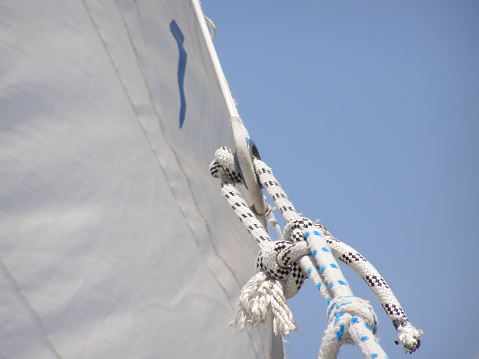 a rope on the jib of a sailboat with a blue sky as background