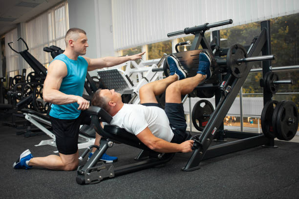 A young coach teaches and shows a person correct technique of performing an exercise on a simulator. Healthy lifestyle, weight loss. fat clients, body positivity, model size plus.