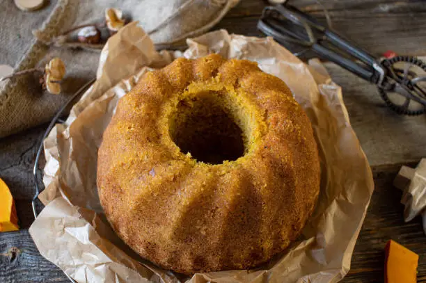 Fresh and homemade baked bundt cake with hokkaido pumpkin and hazelnuts. Still warm. Served on rustic and wooden table. Closeup and top view