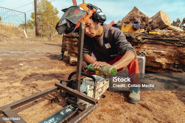 Lumberjack Pouring Oil Into The Chainsaw Oil Tank Stock Photo - Download Image Now - 30-34 Years, Adult, Central Asian Ethnicity