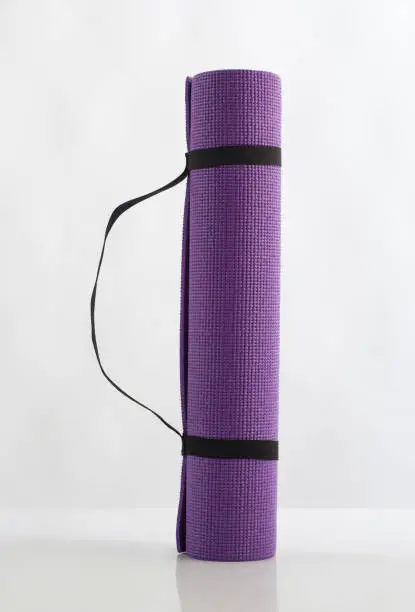 Rolled up purple yoga mat isolated on white background
