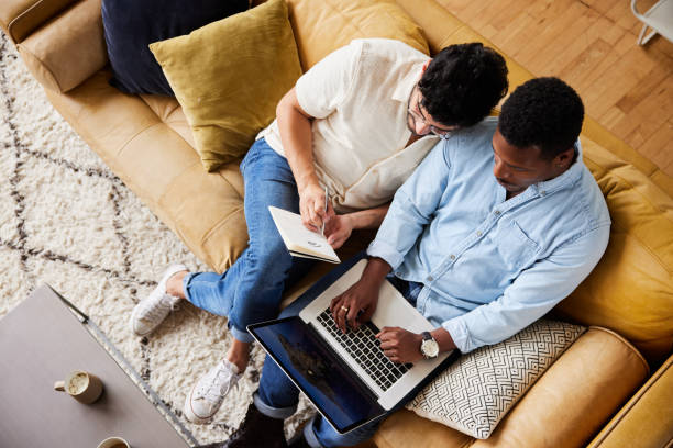 istock Young gay couple using a laptop while relaxing on their sofa 1346180166
