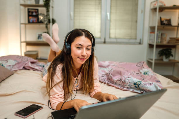 istock Young woman in pajamas on bed at home working using on laptop 1346182142