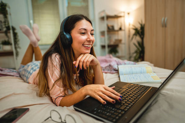 istock Young woman in pajamas on bed at home working using on laptop 1346182178