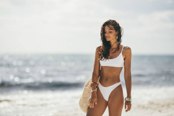 mujer bronceada en bikini blanco en la playa de verano - beach body fotografías e imágenes de stock
