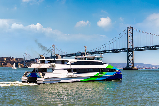 Ferry ship against Oakland Bay Bridge in San Francisco, California, USA