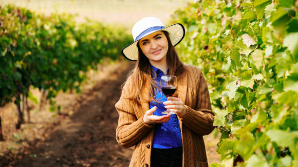 Attractive winemaker woman holding a glass of red wine in her hand and looking at the camera Attractive winemaker woman holding a glass of red wine in her hand and looking at the camera. female with hat in thew vineyard moldova stock pictures, royalty-free photos & images