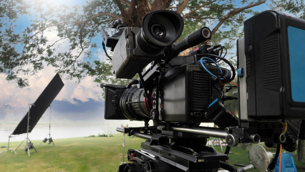 movie camera. behind the video camera that for recording film commercial or movie at outdoor location. 35 mm film styled 4k digital camera and tripod dolly crane for video production. film industry. - movie location imagens e fotografias de stock