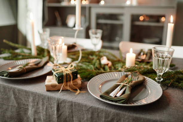 Elegant Dining Table on Christmas with Candles Background image of cozy dining room decorated for Christmas with candles lit and fresh fir branches, copy space place setting table plate dining table stock pictures, royalty-free photos & images