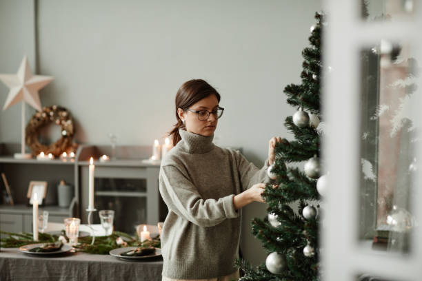 istock Young Woman Decorating Christmas Tree at Home 1346201658