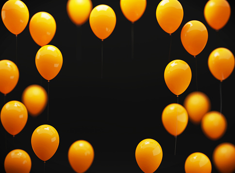 Yellow balloons sitting over black background. Horizontal composition with copy space.