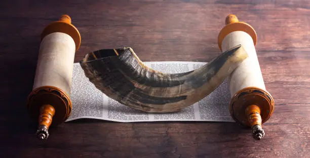 Photo of A Shofar Rams Horn and a Tora Scroll on a Wooden Table