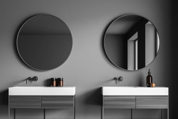 istock Dark grey bathroom vanity area with two round mirrors 1346204733