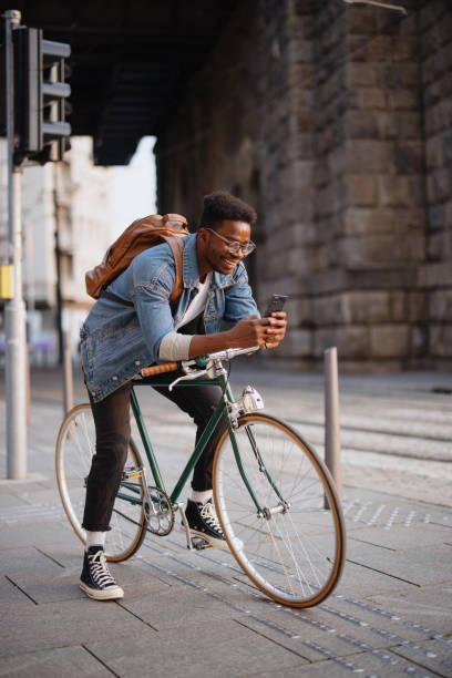 istock Handsome man sitting on the bike using smartphone for text messages 1346206249