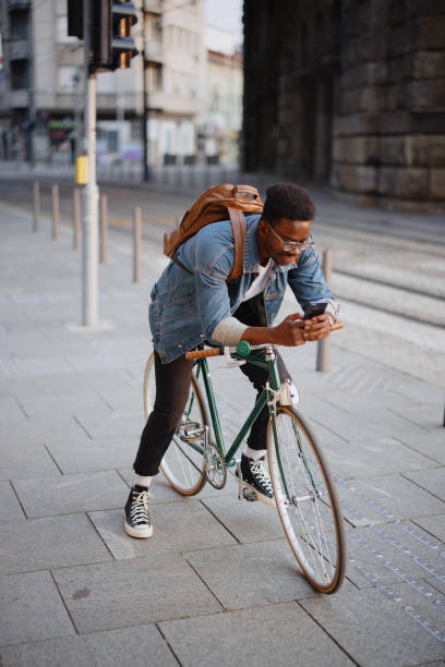 istock Handsome man sitting on the bike using smartphone for text messages 1346206350