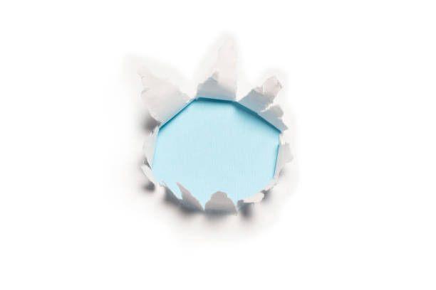 istock A hole in a white paper on a blue background. 1346206746