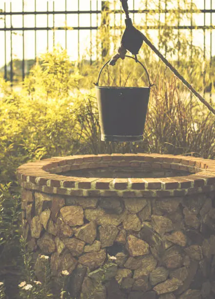 bucket scoop water Vintage image of countryside garden with water well in rustic village