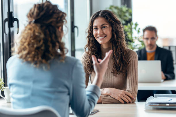 istock Beautiful real-estate agent showing house plans on electronic tablet while talking to beautiful woman about buying the house in a real estate 1346208397