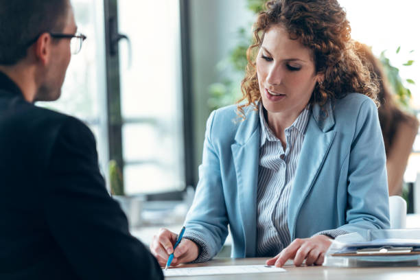 istock Beautiful real-estate agent showing house plans on electronic tablet while talking to mature man about buying the house in a real estate 1346208670