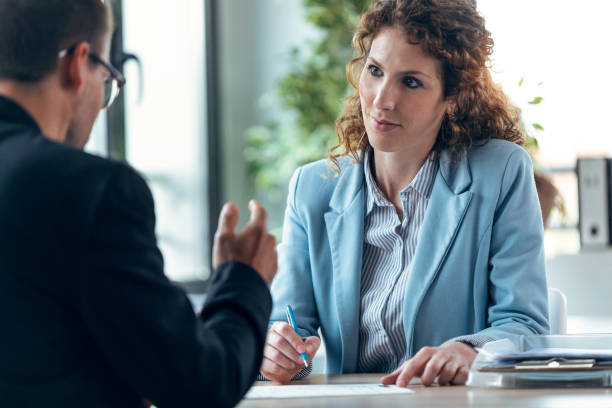 istock Beautiful real-estate agent showing house plans on electronic tablet while talking to mature man about buying the house in a real estate 1346209106