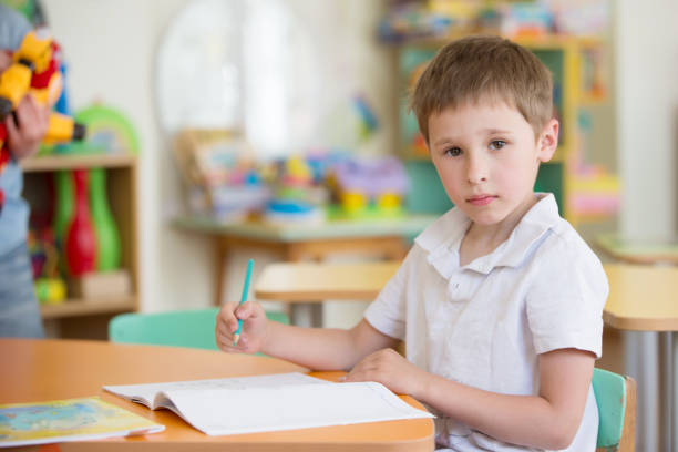 istock A preschool boy at a table in class with a notebook and pen 1346209203