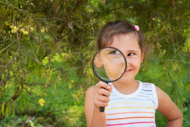 istock Exploring girl with magnifying glass in nature 1346212493