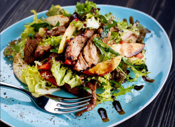 istock Veal salad with lettuce, apple, pear and tomato on blue plate on dark wooden background, copy space. Restaurant food, close up. Meat salad 1346217607