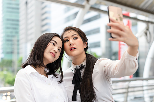 Business women in white dresses taking selfie with mobile phone