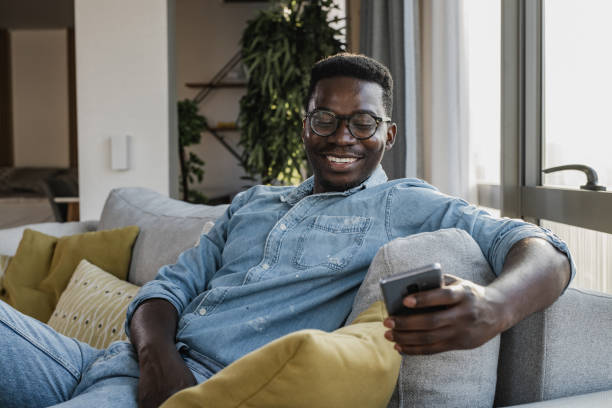 istock Young man relaxing on the couch and using smart phone 1346220335