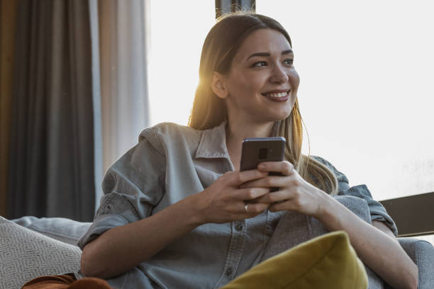 istock Young woman relaxing at home and using smart phone 1346221458