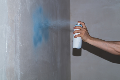 Spray can in the hand. spraying paint on the wall. painting process