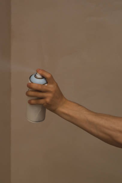 istock Spray can in hand. spraying paint on the wall. painting process 1346222869