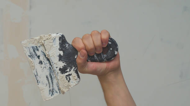 istock Hand holds construction spatula with putty. trowel with spackling. renovation process 1346223601