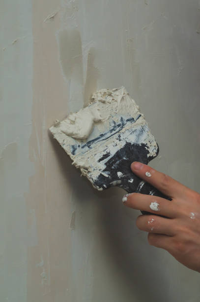 istock Hand holds construction spatula with putty. trowel with spackling. renovation process 1346223757
