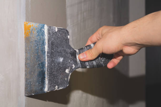istock Hand holds construction spatula with putty. trowel with spackling. renovation process 1346223816