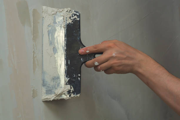 istock Hand holds construction spatula with putty. trowel with spackling. renovation process 1346223860