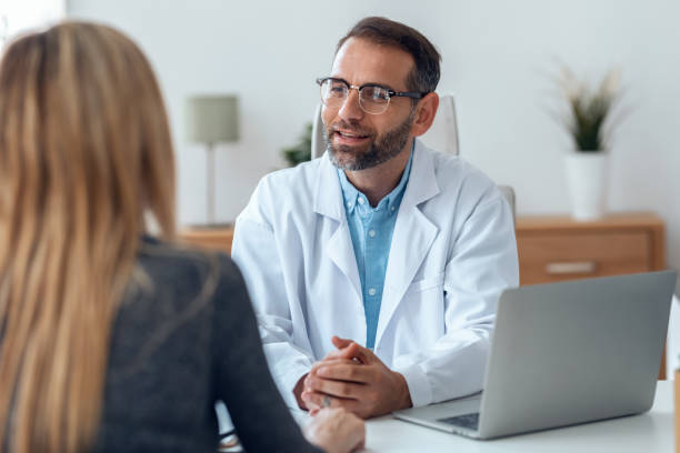 tiro de médico bonito maduro falando enquanto explicava o tratamento médico ao paciente na consulta. - medical accessories - fotografias e filmes do acervo