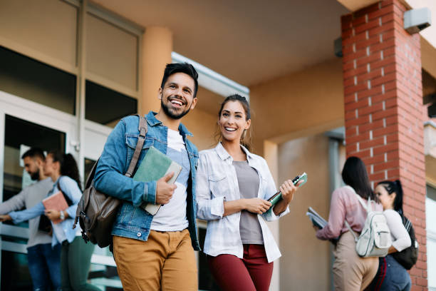 Young happy friends getting outside of university building after the lecture. Happy university student and his female friend walking after the lecture at campus. university student stock pictures, royalty-free photos & images