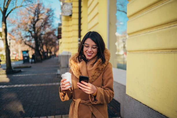 istock Young hispanic woman using smartphone and drinking coffee takeaway 1346226089