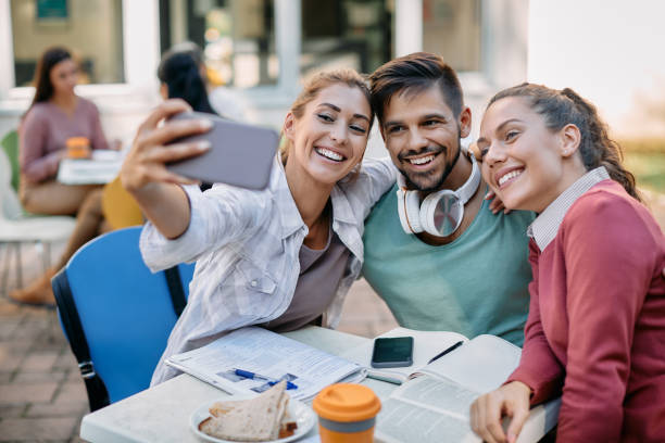 istock Group of happy university friends taking selfie while studying on lunch break at campus. 1346226955