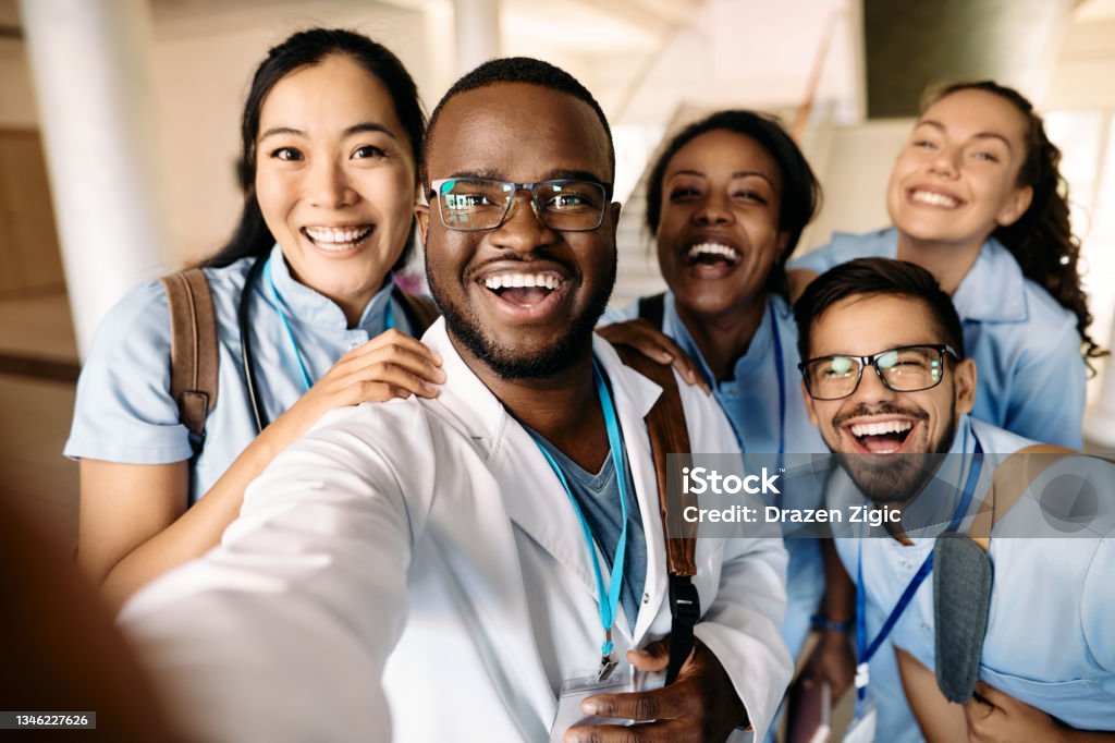 Cheerful medical students taking selfie and having fun at the university. Multi-ethnic group of happy students having fun wile taking selfie at medical university. Nurse Stock Photo
