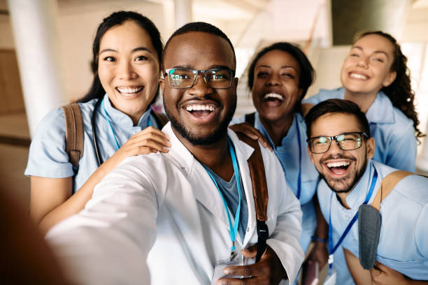 Cheerful medical students taking selfie and having fun at the university. Multi-ethnic group of happy students having fun wile taking selfie at medical university. medical occupation stock pictures, royalty-free photos & images