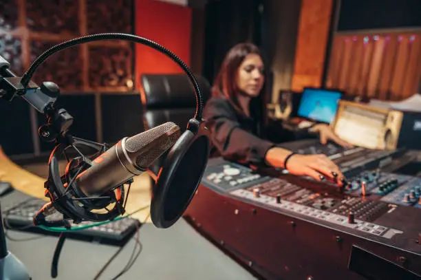 Photo of Young woman music producer working on a mixing soundboard while in her studio