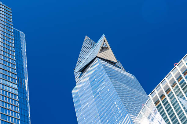 A skyscraper in New York City Manhattan.  This silver sleek modern skyscraper contrasts with a blue sky.