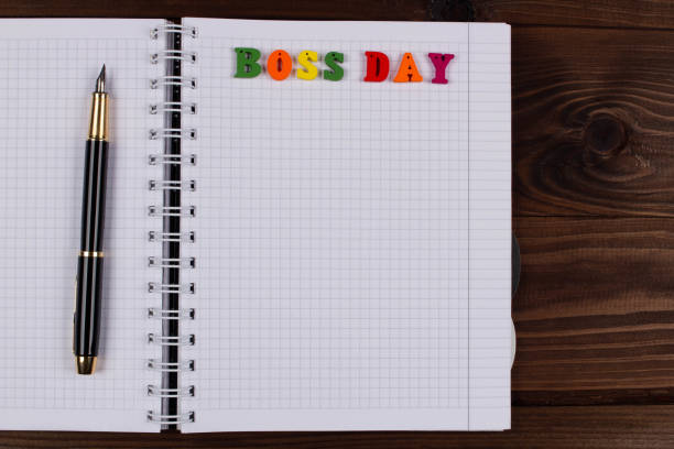 istock National Happy Boss Day. Multicolored colorful letters in a squared exercise book with pen on the table. Boss’s Day office greeting card with copy space for text. Close-Up. Top view. View from above 1346235280