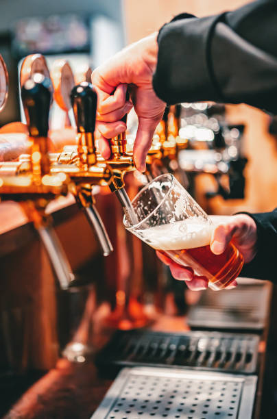 istock bartender hand at beer tap pouring a draught beer in glass serving in a bar or pub 1346239964